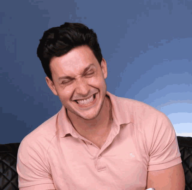 a man wearing a pink polo shirt has his eyes closed
