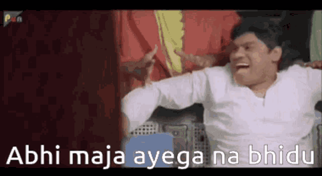 a man is laughing with his arms outstretched and the words abhi maja ayega na bhide on the bottom .