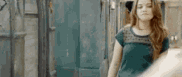 a woman in a green shirt is walking down a street in front of a building .