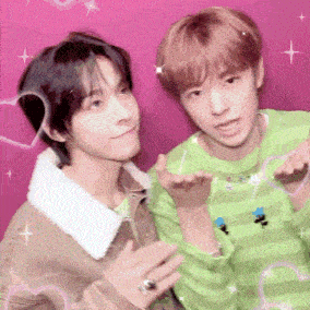 two young men are posing for a picture in front of a pink wall .