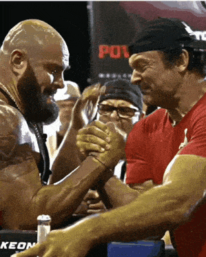 two men arm wrestling in front of a sign that says pow