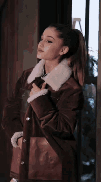 a woman is wearing a brown jacket with a white collar