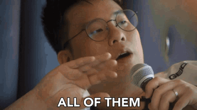 a man with glasses is holding a microphone and says " all of them "