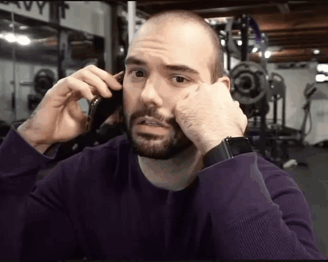 a man in a purple sweater is talking on a cell phone