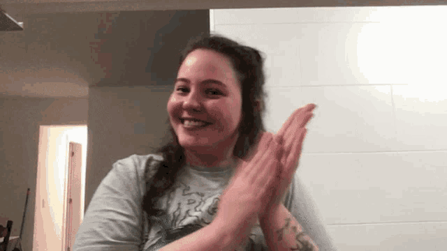 a woman with a tattoo on her arm is clapping her hands together