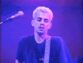 a man is playing a bass guitar on a stage in front of a microphone