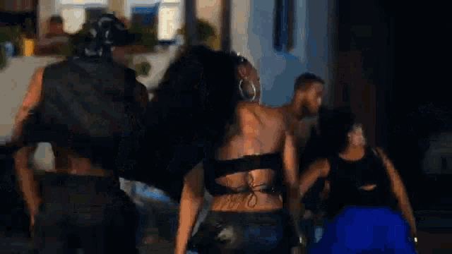 a group of people are dancing on the street in front of a house