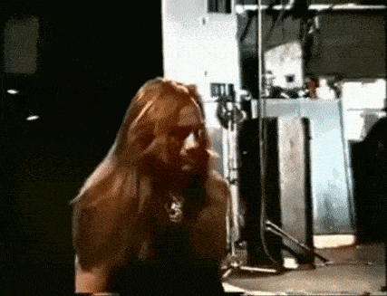 a woman with long hair is standing in a dark room in front of a microphone .