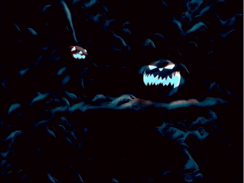 two carved pumpkins with evil faces are lit up in the dark