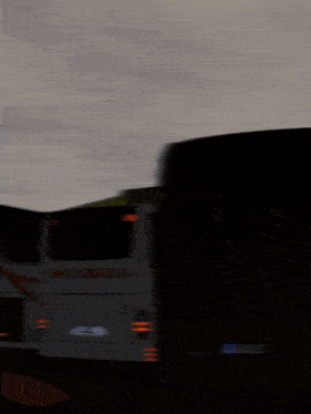 several buses are parked in a dark parking lot and one of them has the word ansel on the back