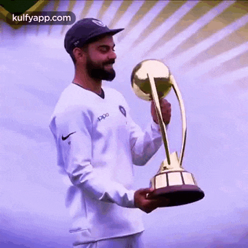 a man in a white shirt and black hat is holding a trophy .