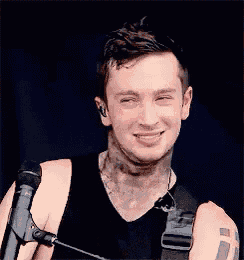 a young man is smiling while holding a microphone in his hand .