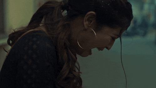 a woman wearing hoop earrings and a ponytail is crying