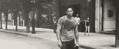 a black and white photo of a man walking down a sidewalk .