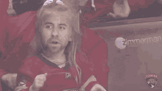 a man with long blonde hair and a beard is wearing a red jersey
