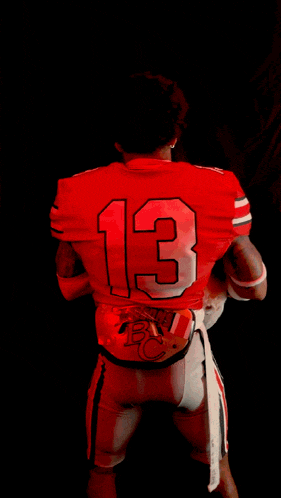 a man wearing sunglasses and a red jersey with the number 32 on it holds a small dog