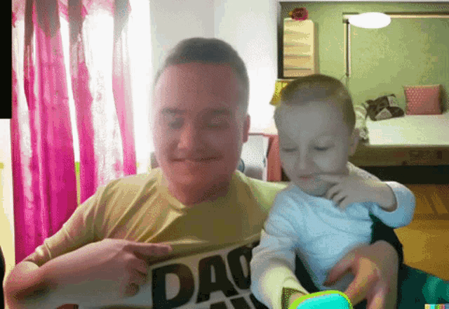 a man wearing a shirt that says dad is holding a child