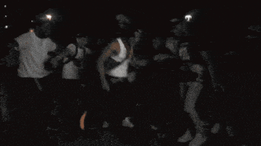 a crowd of people are gathered in a dark room and one of them is wearing a shirt that says nike