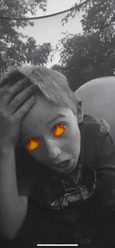 a black and white photo of a young boy with glowing red eyes
