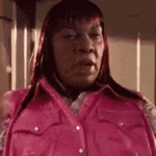 a woman in a pink vest and shirt is making a funny face .
