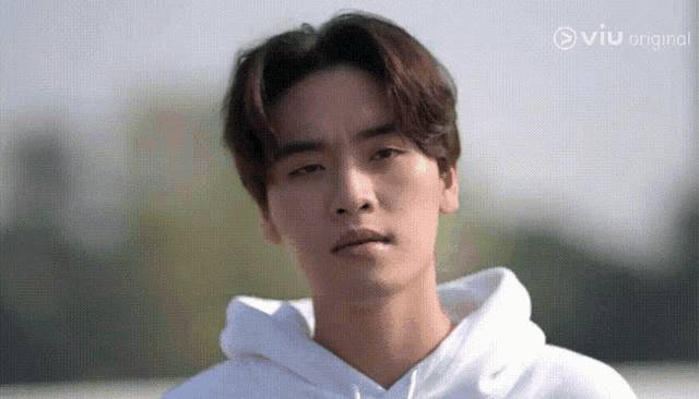 a young man is wearing a white hoodie and making a funny face .