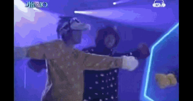 two people are dancing on a stage with their arms outstretched in front of a blue background .