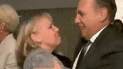 a man in a suit and tie is kissing a woman .