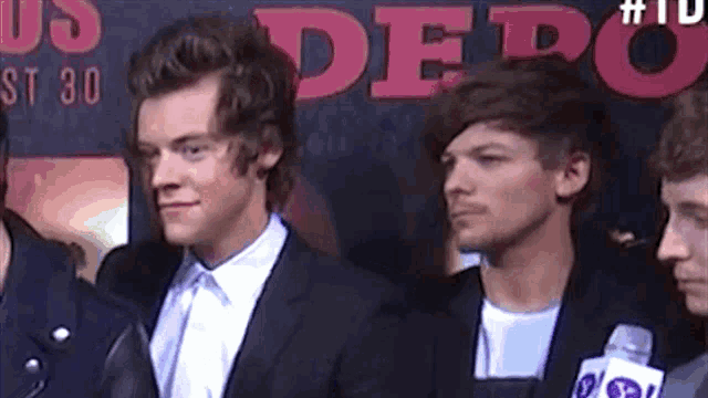 harry styles and louis tomlinson are standing next to each other in front of a sign that says us depot .
