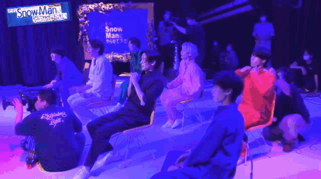 a group of people sitting in front of a screen that says snow man