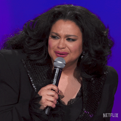 a woman singing into a microphone with the words what written on the bottom