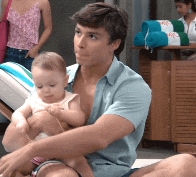 a man is holding a baby in front of a row of towels that say mc on them