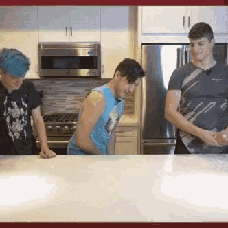 three men are standing in a kitchen looking at something