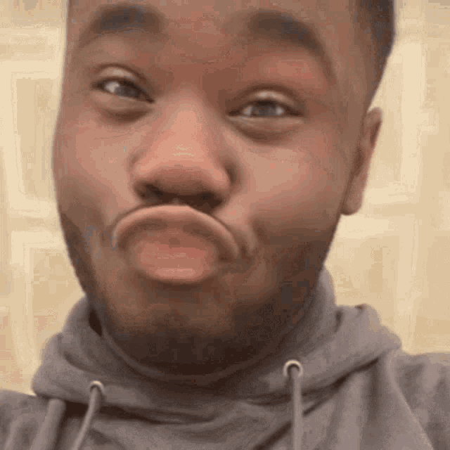 a man with a beard is making a funny face while wearing a grey hoodie .