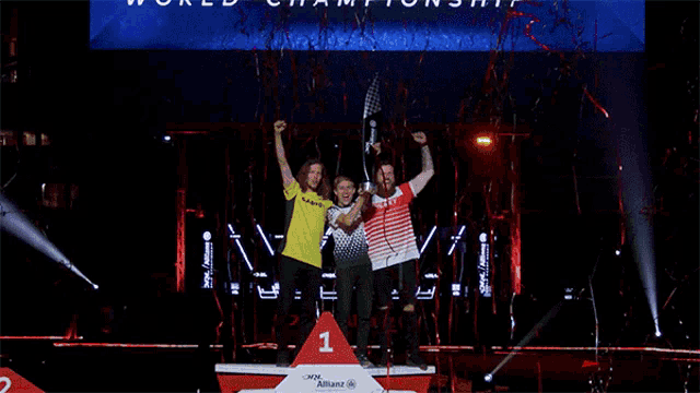three people are standing on a stage with a podium that has the number 1 on it