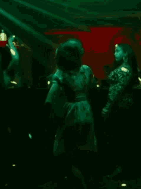 a crowd of people are dancing in a dark room with a green background