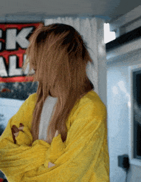 a woman in a yellow jacket stands in front of a sign that says ck
