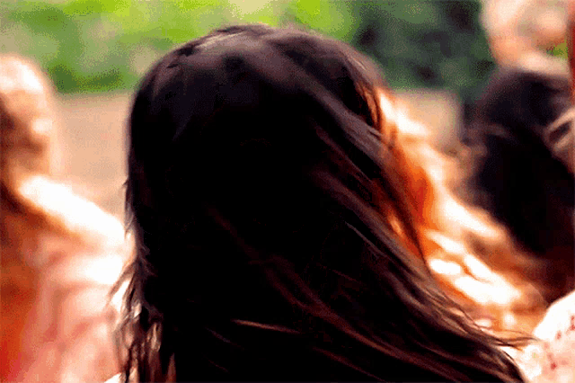 a woman with long dark hair is standing in front of a crowd .