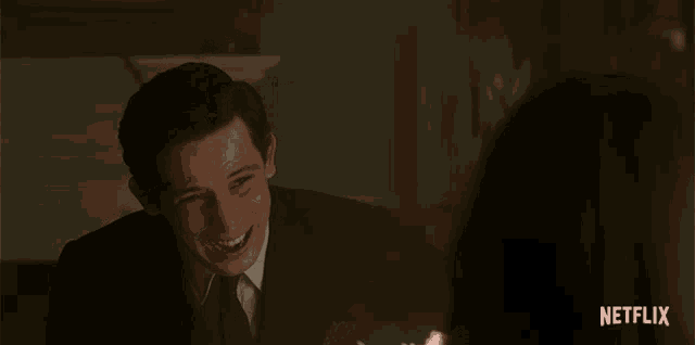 a man sitting at a table with a napkin in his hand and a netflix logo on the bottom right