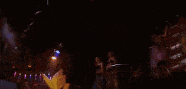 a group of people are dancing in a club with a man in a blue shirt