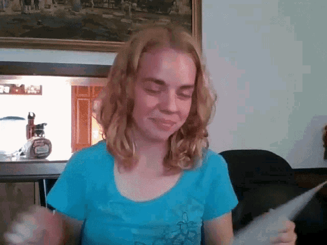 a young girl in a blue shirt is holding a piece of paper