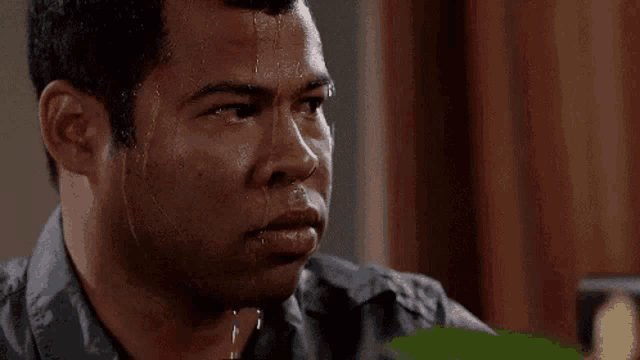 a man with sweat coming out of his face is looking at something .