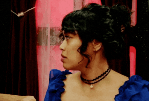 a woman in a blue dress has a pearl necklace