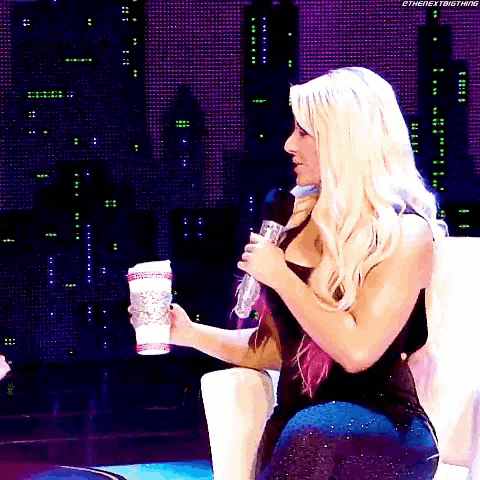 a woman is sitting in a chair holding a microphone and a cup of coffee .
