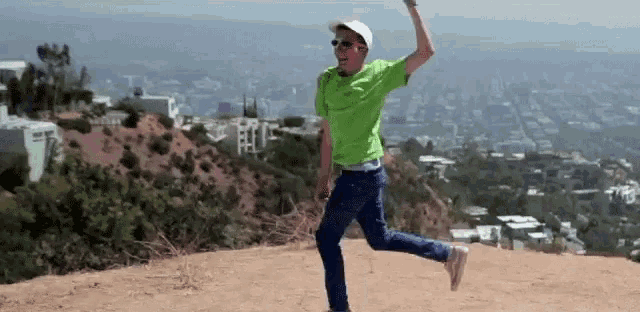 a man in a green shirt is running on a hill with a city in the background