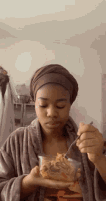 a woman wearing a head scarf is eating food with a fork