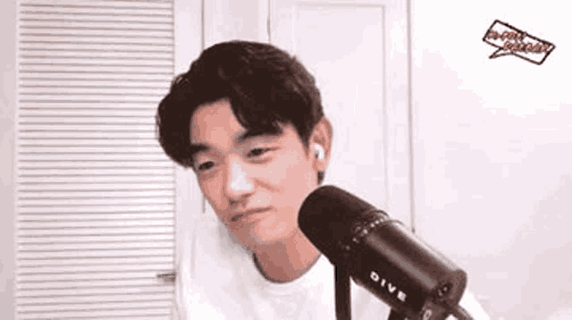 a man is sitting in front of a microphone and making a funny face .
