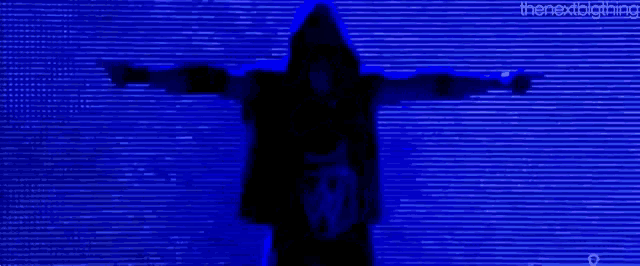 a person in a hooded jacket is standing in front of a blue screen .