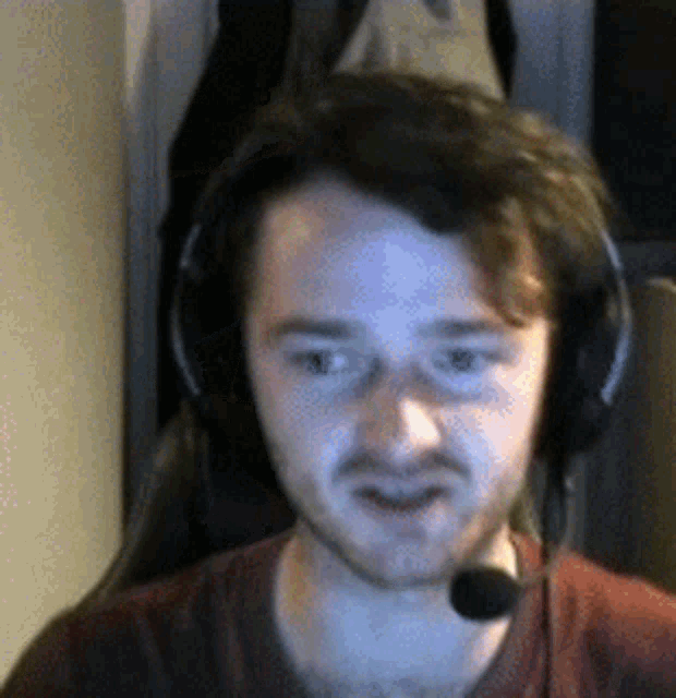 a man wearing headphones and a microphone is sitting in a chair .