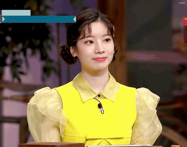 a woman wearing a yellow vest and a yellow shirt with ruffled sleeves