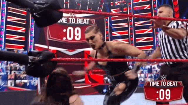 a woman in a wrestling ring with a time to beat sign